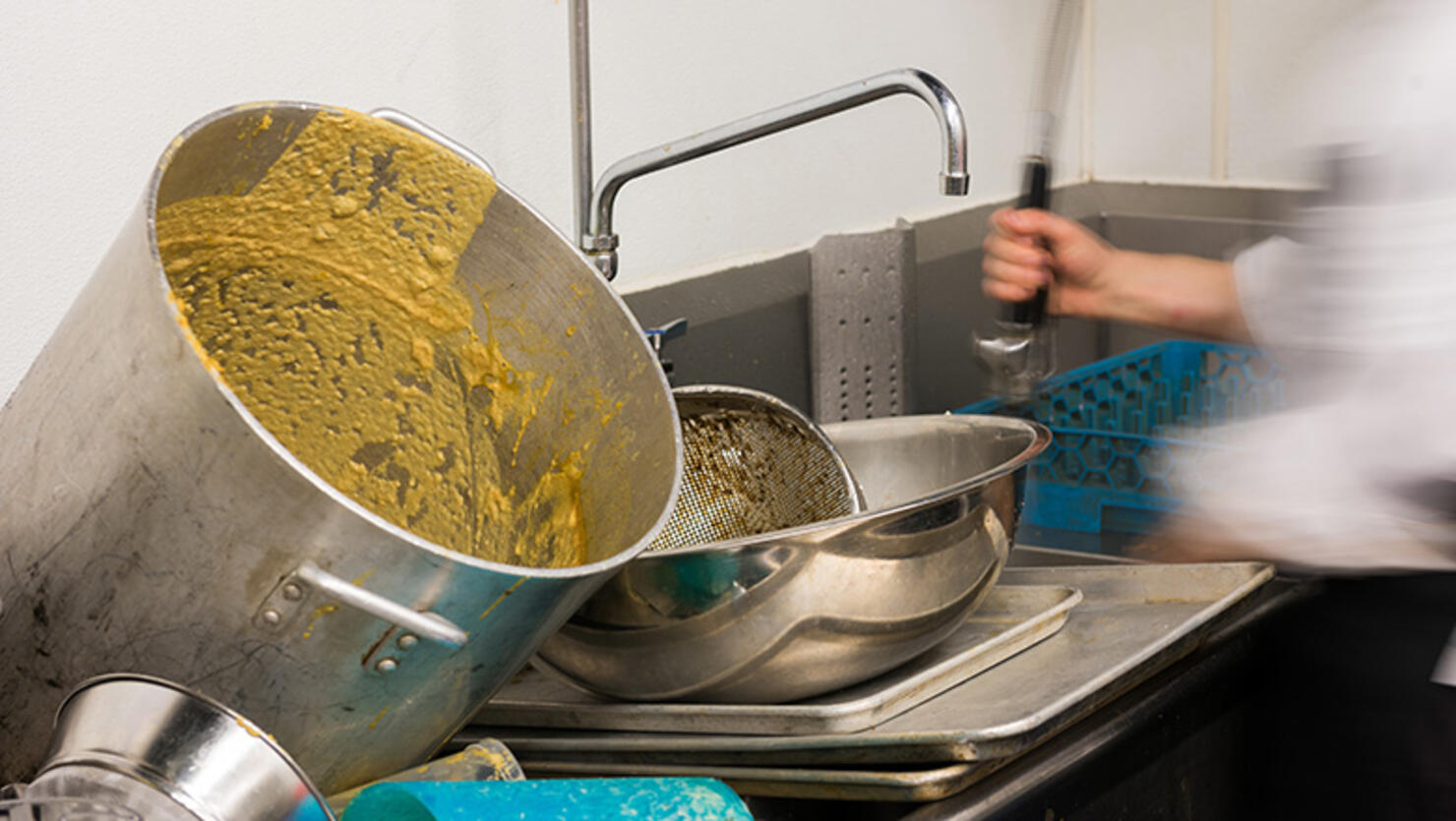 A person washing dirty pots and pans. 