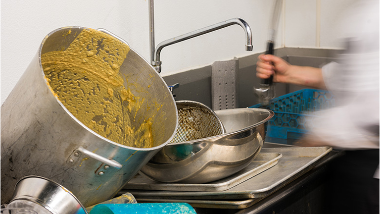 A person washing dirty pots and pans. 