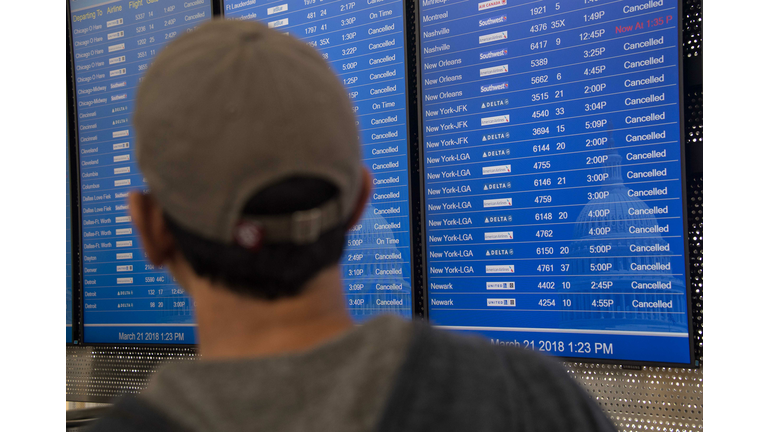 A person looks at a board showing many cancelled flights at Reagan National Airport in Arlington, Virginia, on March 21, 2018 as heavy snow hit the northeastern US. The fourth Noreaster in less than three weeks, Winter Storm Toby, is throwing a fresh blanket of snow just as spring begins. / AFP PHOTO / NICHOLAS KAMM (Photo credit should read NICHOLAS KAMM/AFP/Getty Images)