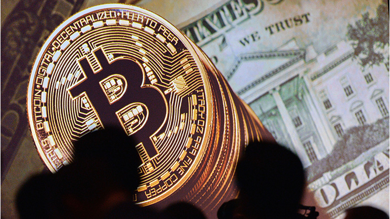 An image of Bitcoin and US currencies is displayed on a screen as delegates listen to a panel of speakers during the Interpol World Congress