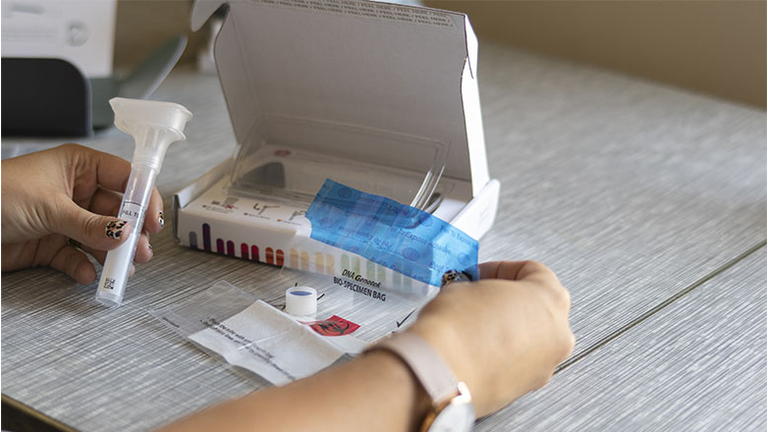 A reporter examines a 23andMe Inc. DNA genetic testing kit 