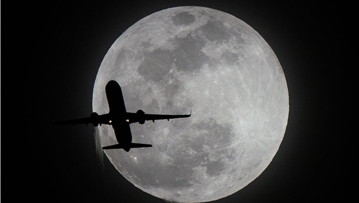 A plane flies past the super moon in Los Angeles,