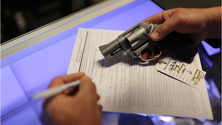Mark O'Connor fills out his Federal background check paperwork as he purchases a handgun at the K&W Gunworks store