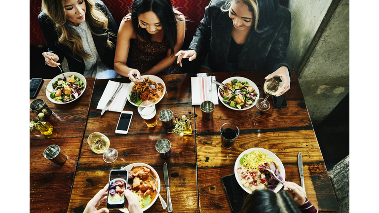 Overhead view of smiling female friends sharing lunch in restaurant