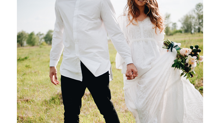 Midsection Of Couple With Holding Hands Walking On Field