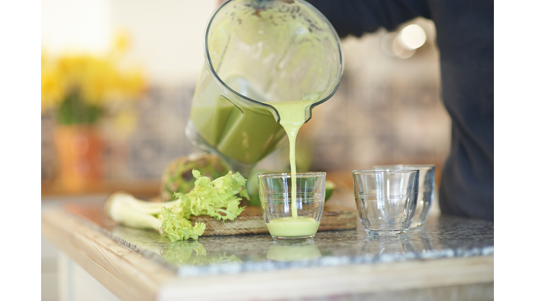 Pouring a fresh smoothie drink in kitchen.