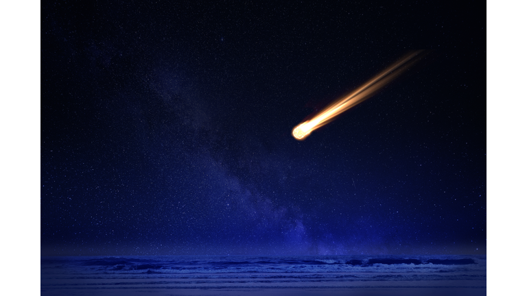 Meteor in night sky falling over ocean
