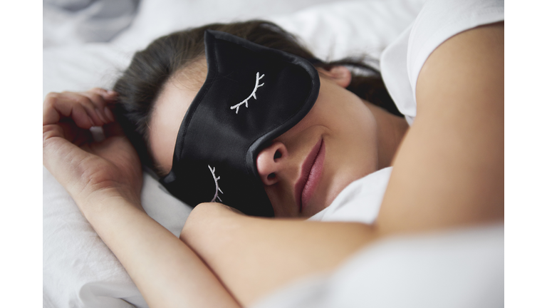 Portrait of young woman with sleep mask in bed