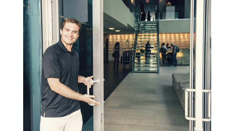 Hispanic bellboy opening hotel door