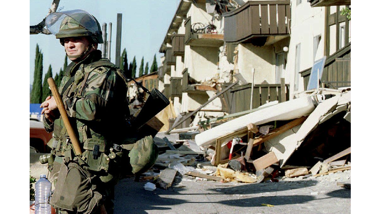 A National Guardsman stands guard outside the ruin