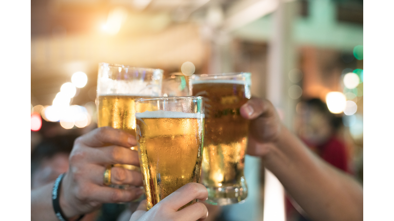 Friends toasting with glasses of light beer at the pub. Beautiful background of the Oktoberfest. A group of young people while relaxing at the bar. fine grain. Soft focus. Shallow DOF.