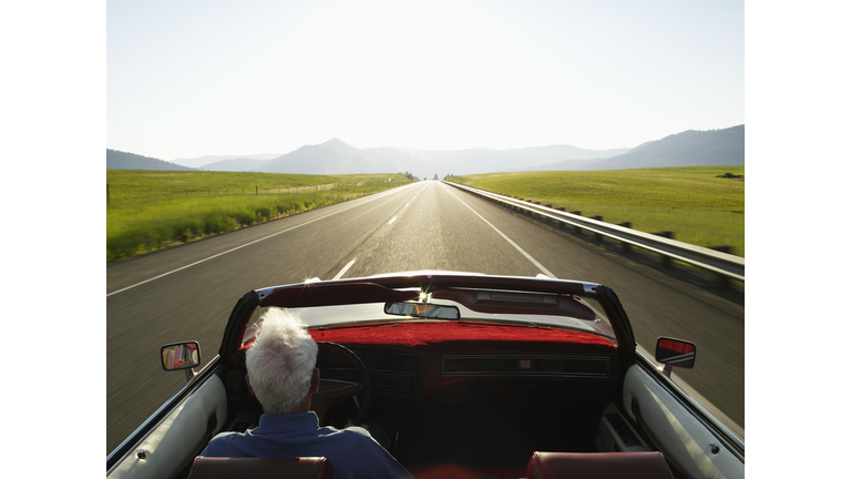 Senior man driving convertible car at sunrise, rear view Cle Elum, Washington, USA, Jul 2006 	Thomas Barwick/Getty Images