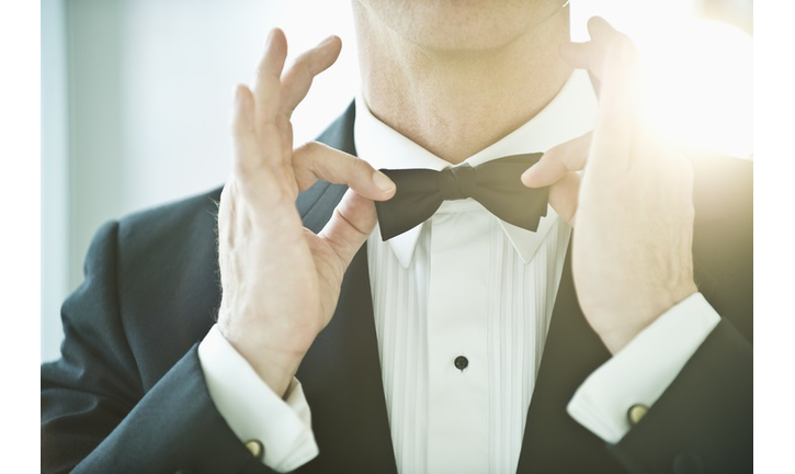 A man in a tuxedo fixing his bowtie