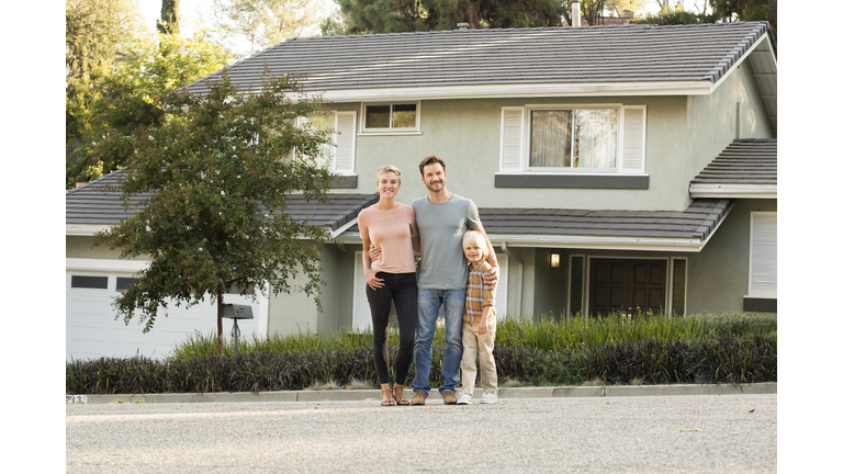 Portrait of smiling parents with boy standing in front of their home