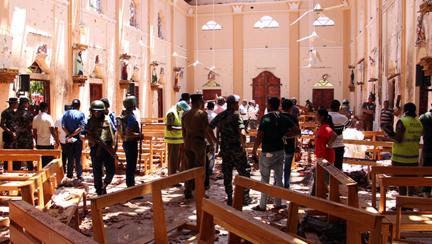 Sri Lankan security personnel walk through debris following an explosion in St Sebastian's Church in Negombo