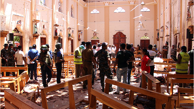 Sri Lankan security personnel walk through debris following an explosion in St Sebastian's Church in Negombo