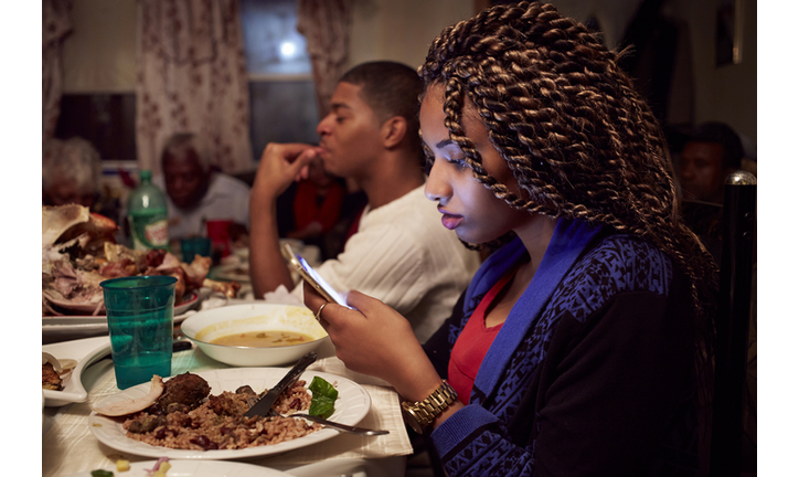 Teenage girl using cell phone at dinner table