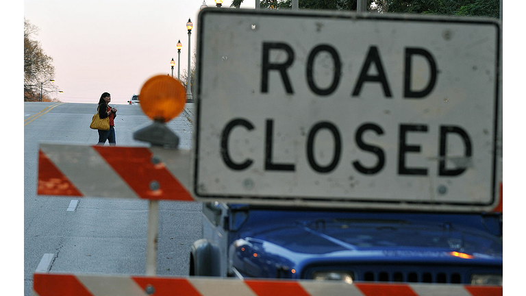 A woman walks past a "road closed" sign