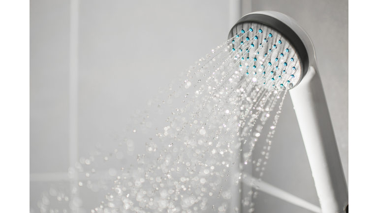 Close-Up Of Shower Head Spraying Water In Bathroom