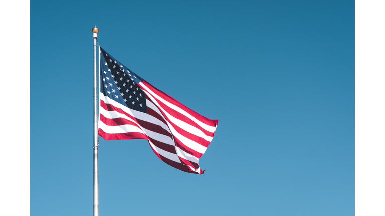 Low Angle View Of American Flag Waving Against Clear Blue Sky