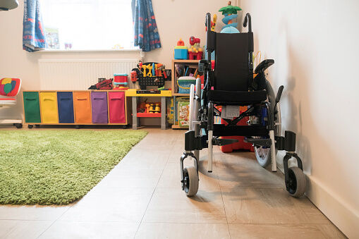 Empty wheelchair and colorful toys arranged at home