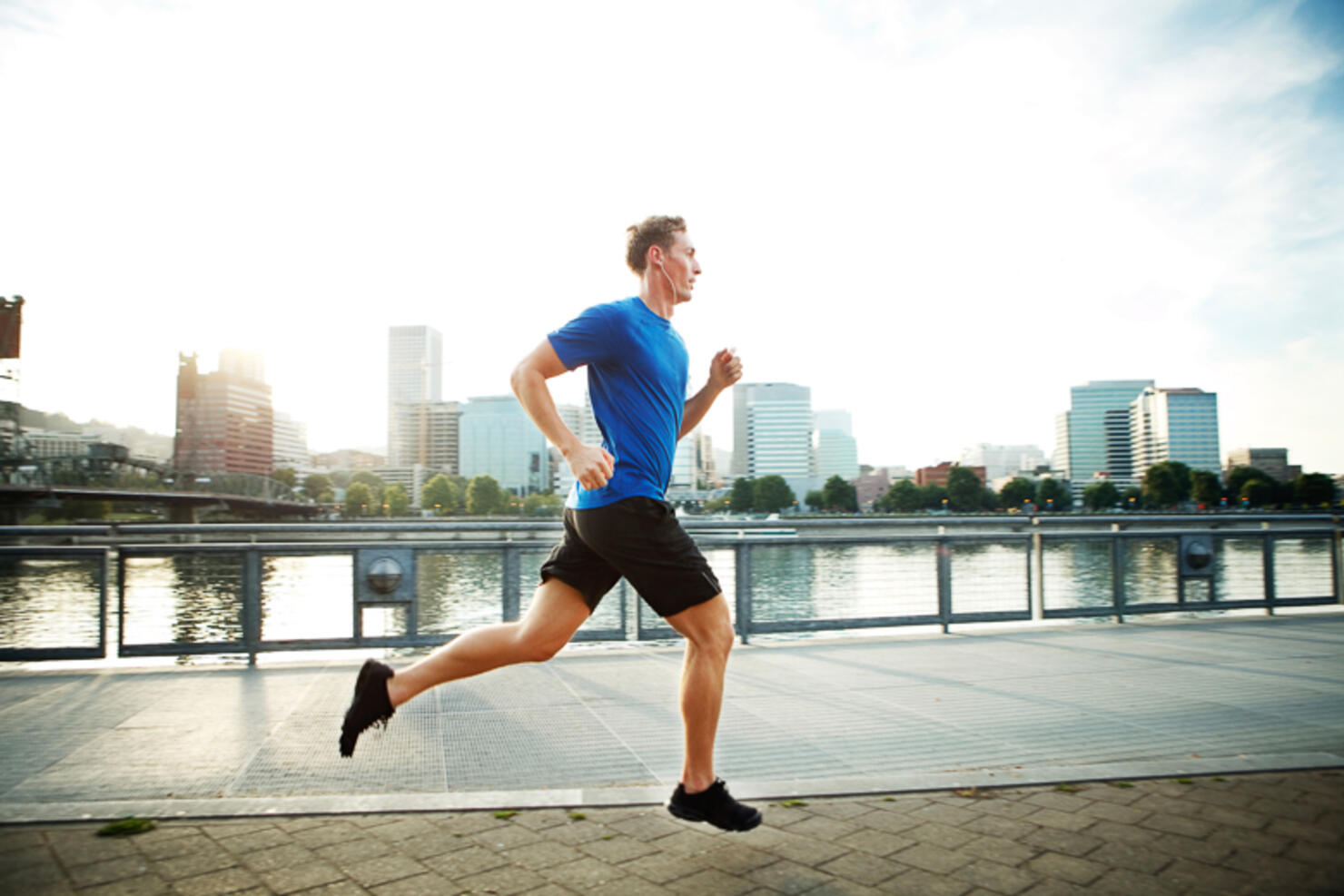 Young man jogging on promenade in city