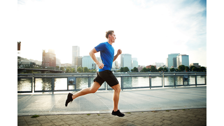 Young man jogging on promenade in city