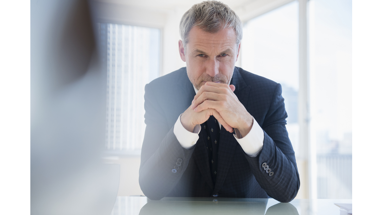 Serious older Caucasian businessman leaning on desk