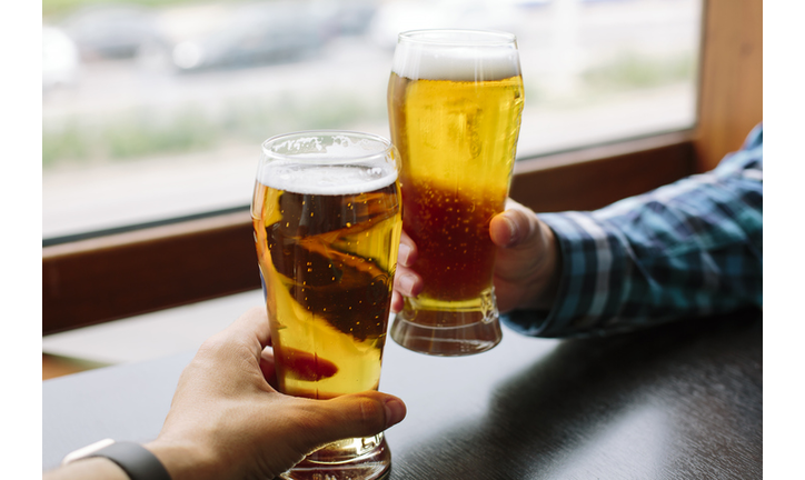 Close up of two men's hands holding beer glasses