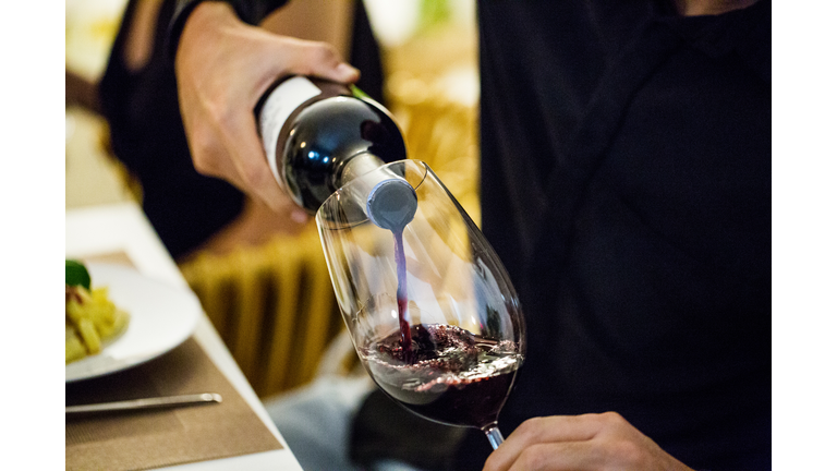 Man pouring red wine in glass during dinner party