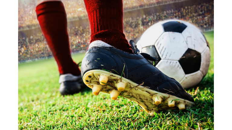 Low Section Of Player Kicking Soccer Ball On Field