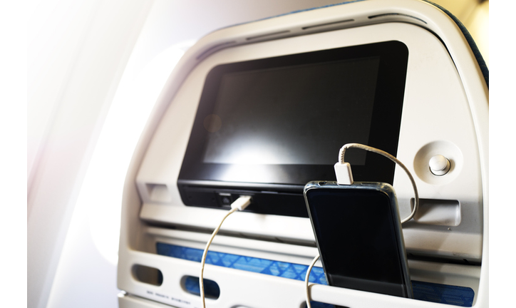 Passenger on a plane using the charger for charge smart phone during flight. Charging station on plane.