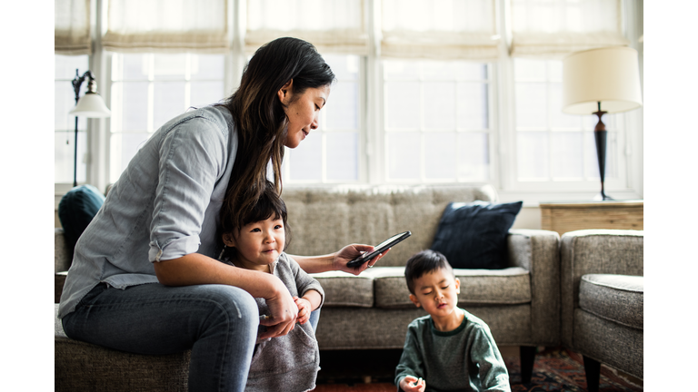 Mother using smartphone with children present