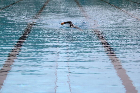 A lone swimmer in a wetsuit practices at