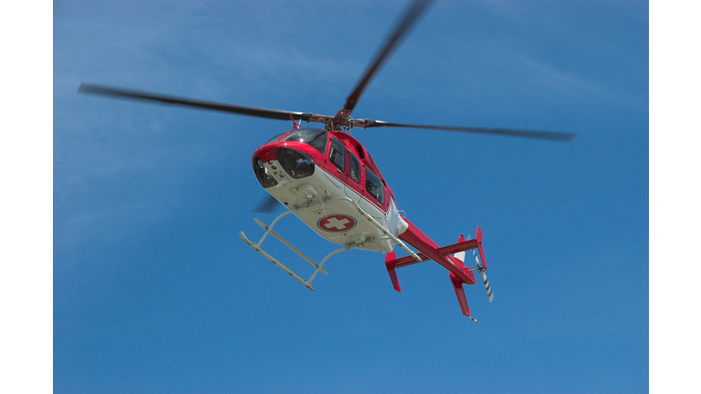 Closeup of flying red helicopter in contrast with blue sky