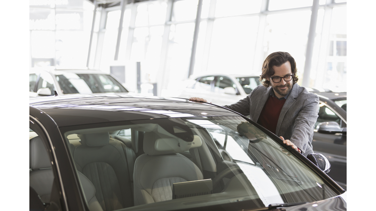 Male customer eyeing new car in car dealership showroom