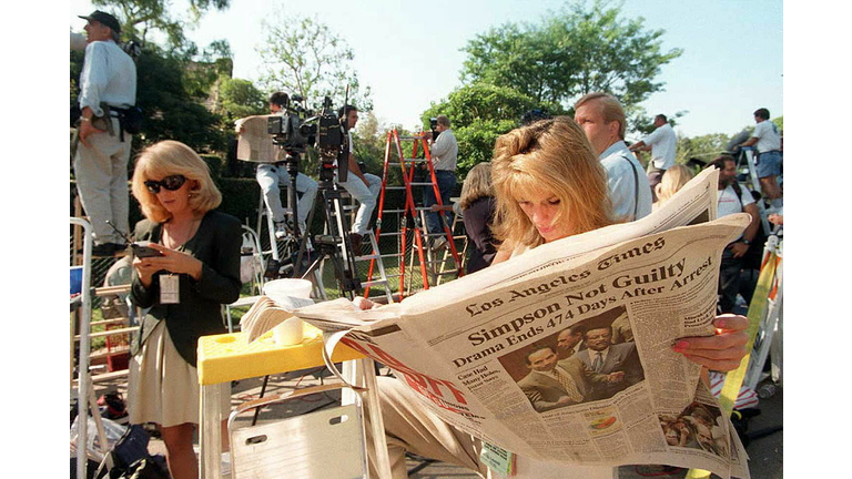 TV reporter Pat Lalama reads a newspaper headlinin