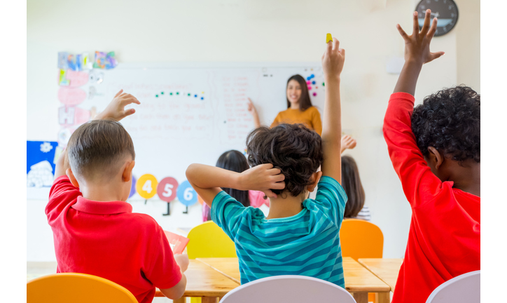 Rear View Of Students Sitting With Teacher