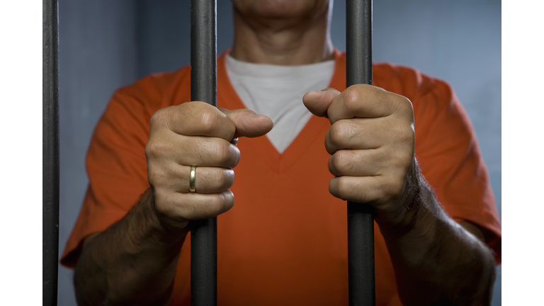 A prisoner standing behind prison bars