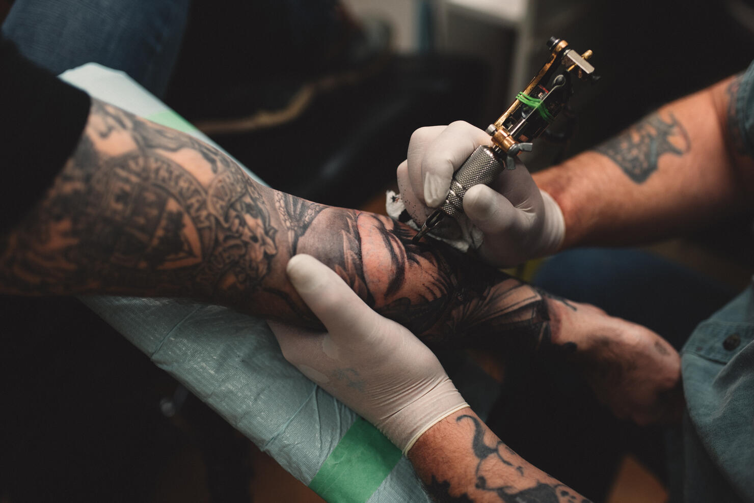 Tattooist tattooing young mans arm, close-up
