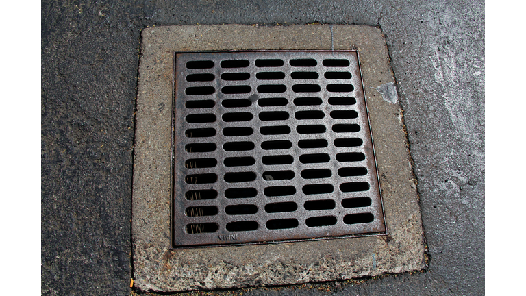Square metal grid cover on manhole in an asphalt sidewalk in New York