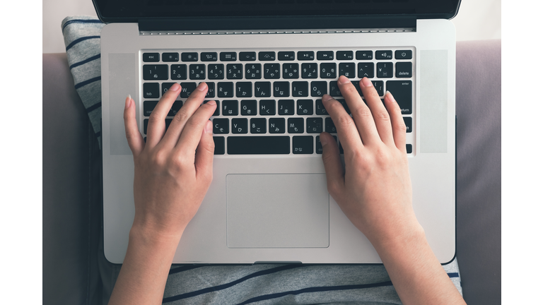 Hand typing laptop above view