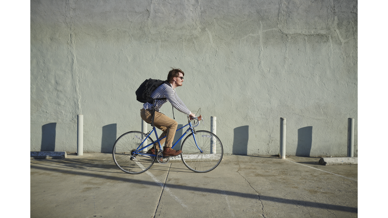 Businessman riding bicycle along concrete wall