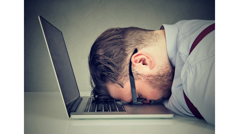 Overworked man lying on laptop
