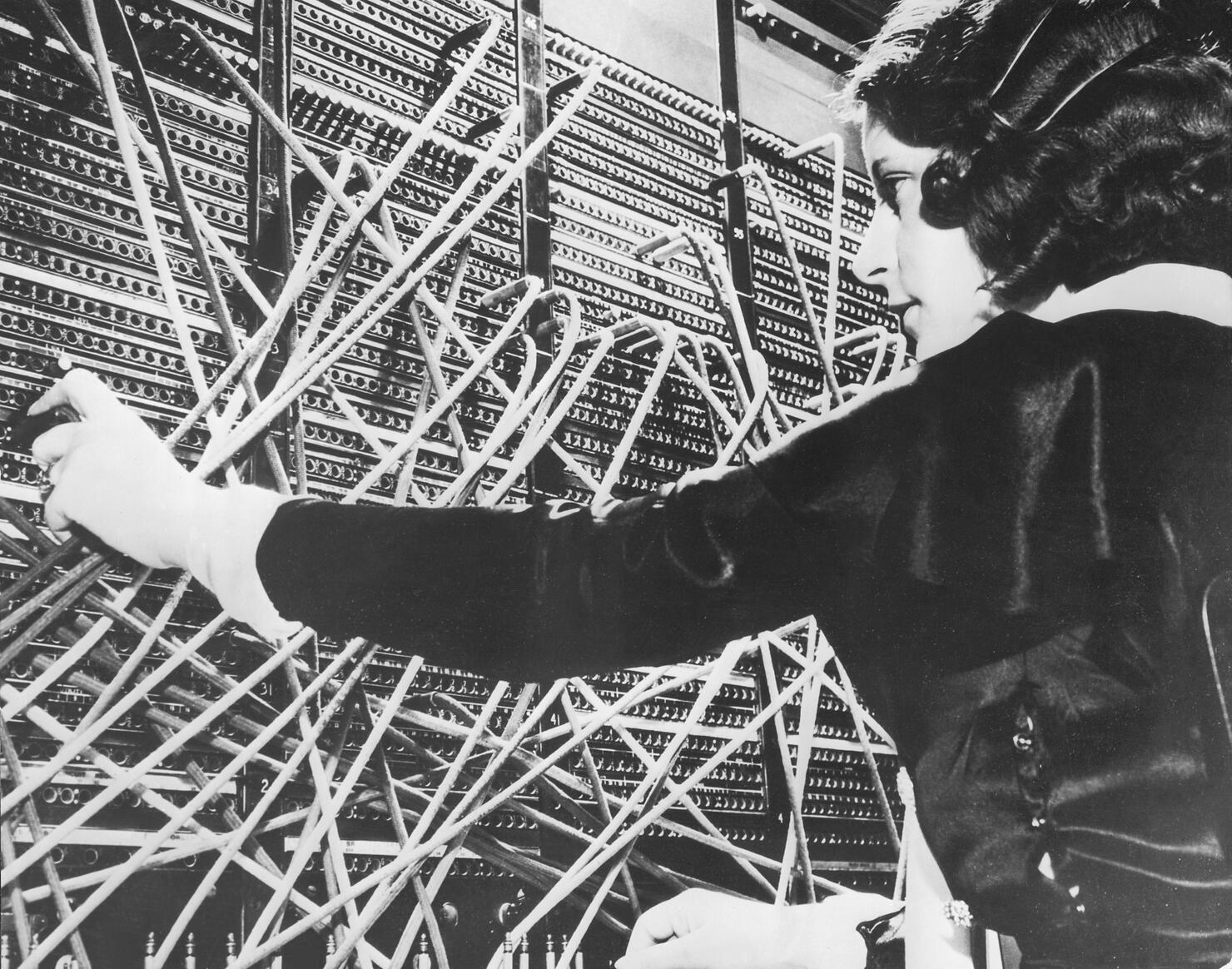 Female telephone switchboard operator connecting caller, close-up (B&W