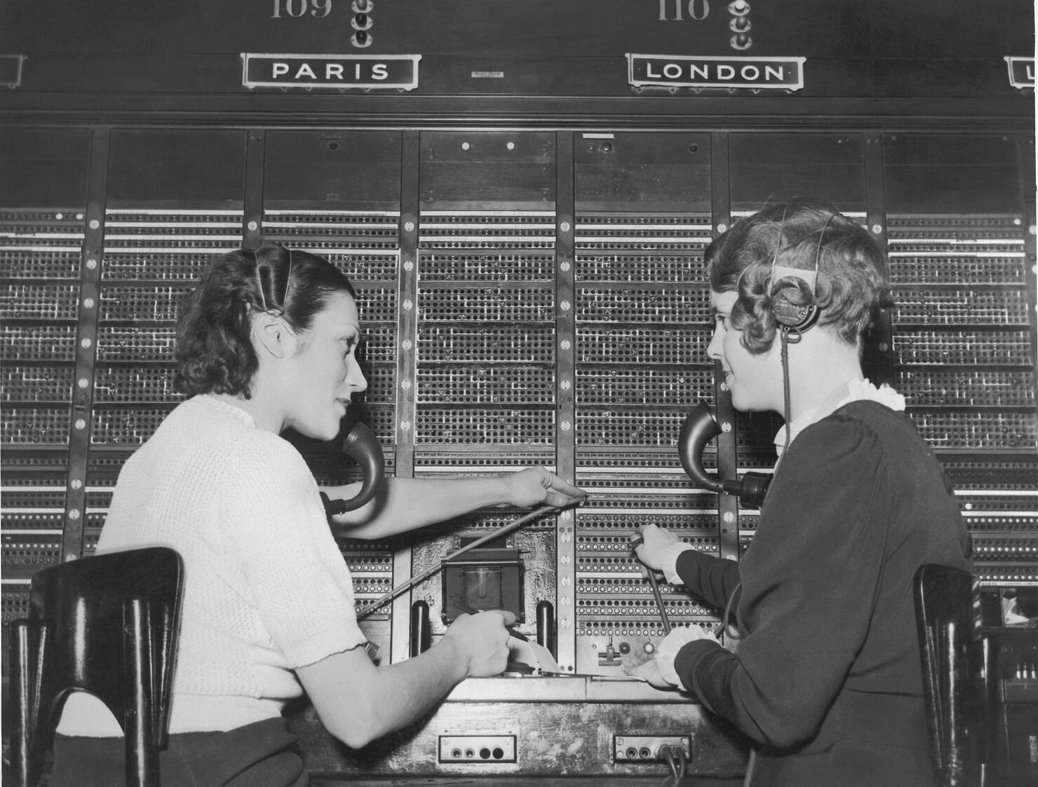 Two female switchboard operators connecting international calls (B&W)