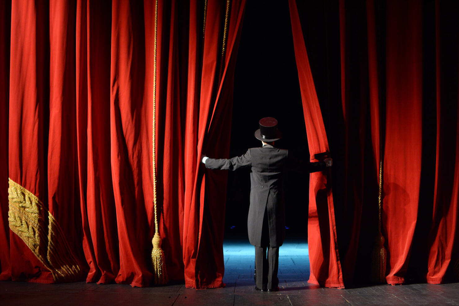 actor in a tuxedo stage curtain opens