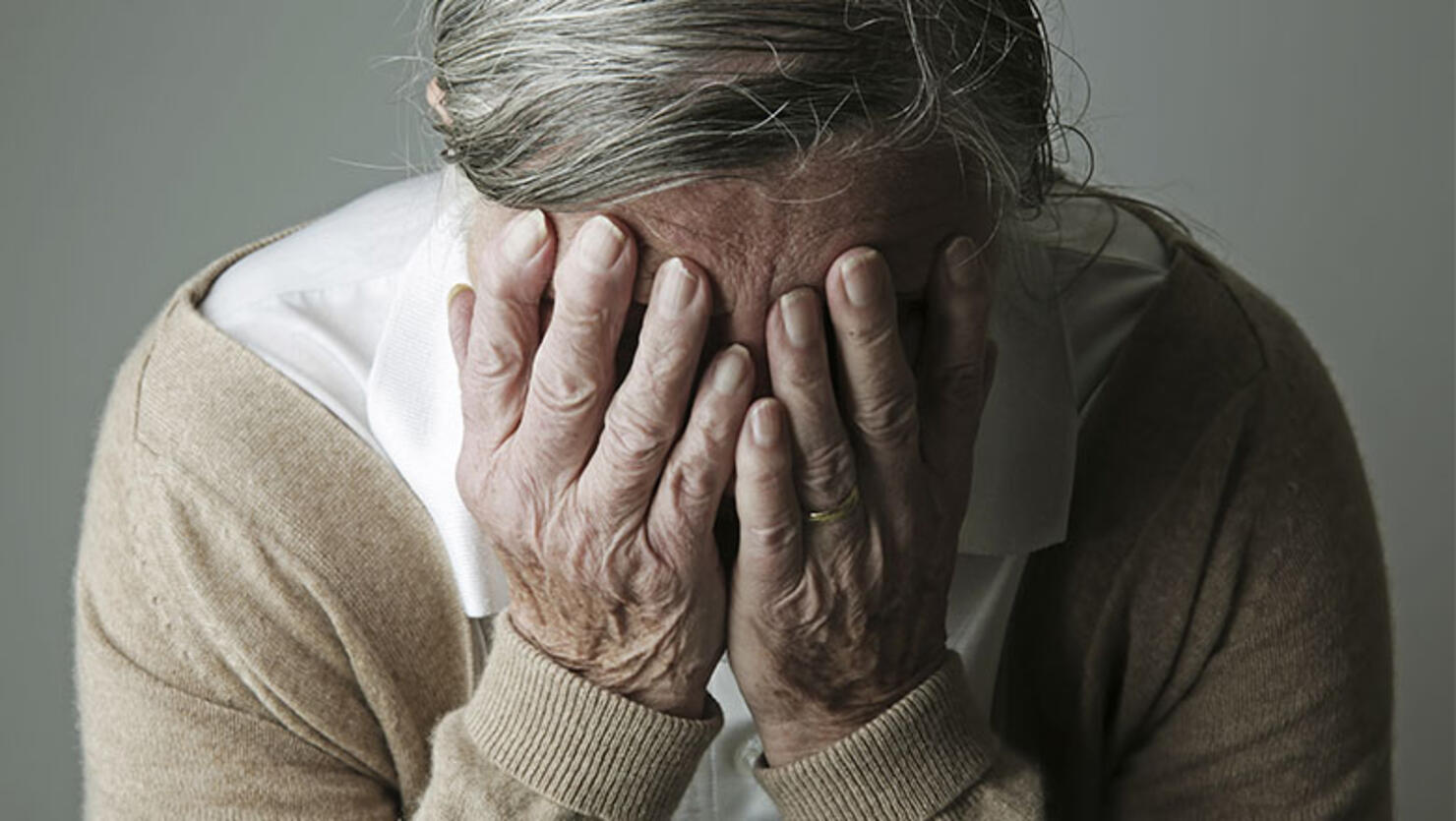 Senior woman covering face with her hands