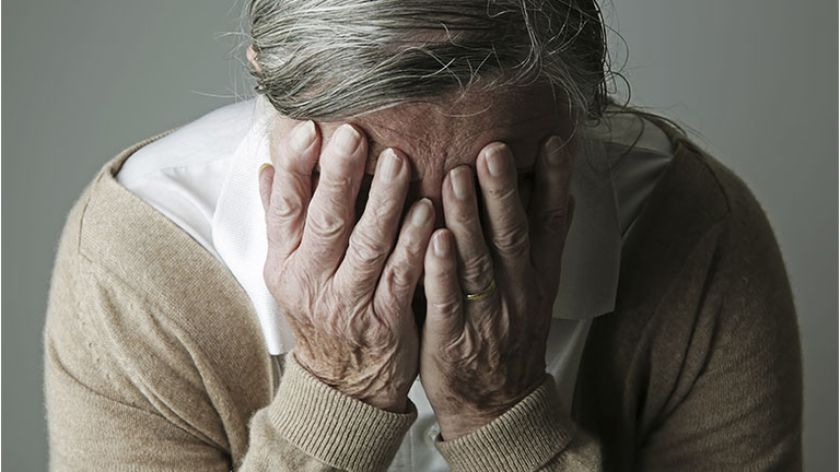 Senior woman covering face with her hands