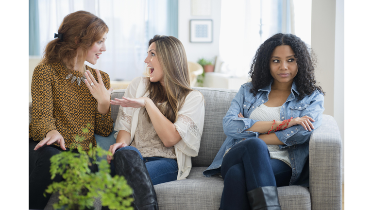 Chatting women ignoring upset friend on sofa